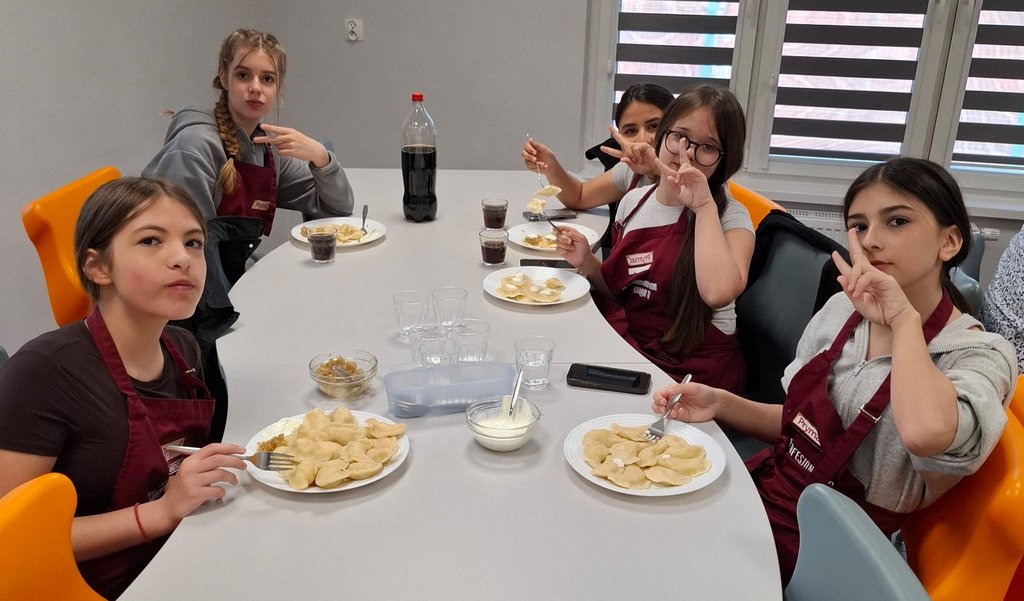 Polnische Schülerinnen essen gemeinsam selbst gemachte Pierogi an einem festlich gedeckten Tisch