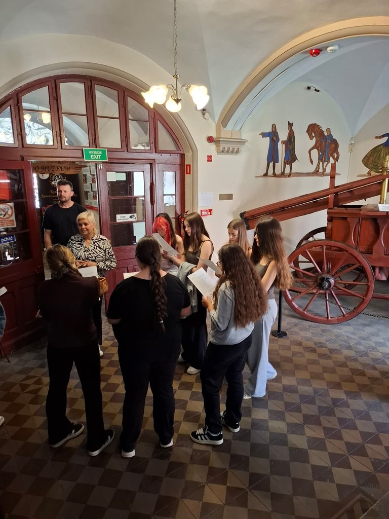 Schülergruppe im gewölbten Eingangssaal des Stadtmuseums Ziębice mit historischer Feuerwehrkutsche